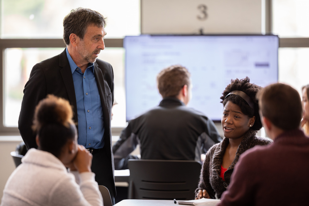 Students group together for a group project and ask the professor questions
