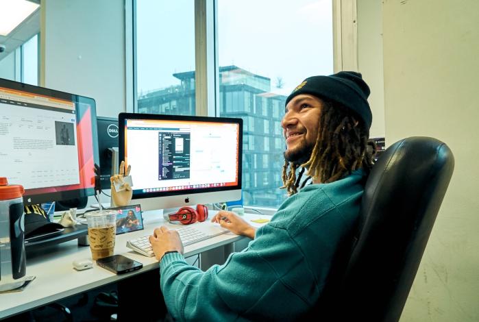 Image: alumni Jordan Harvey sitting at his desk while at work
